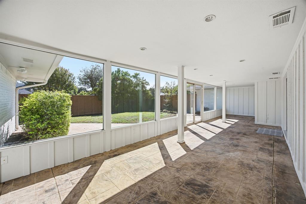 Enclosed patio featuring floor-to-ceiling windows, recessed lighting, vertical paneled walls, and stamped concrete flooring