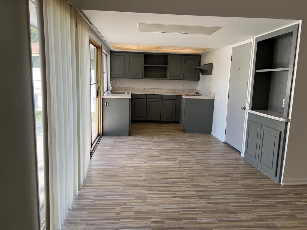 Kitchen area featuring dark cabinetry, stone-finish countertops, wood-finish flooring, built-in shelving, and sliding glass doors