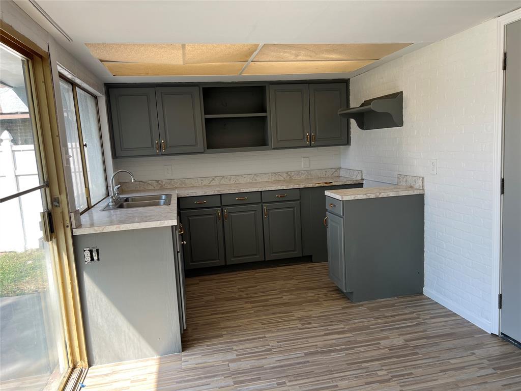 Kitchen featuring grey cabinetry, stone-finish countertops, stainless steel dual-basin sink, drop ceiling panels, and wood-finish flooring