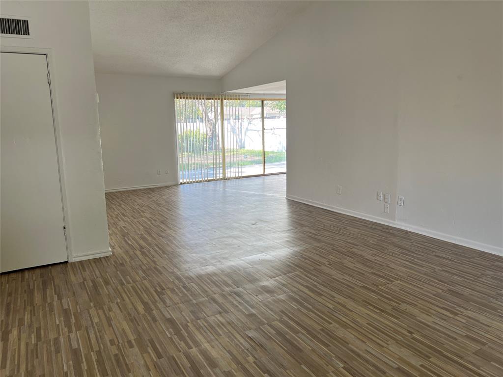 Open-concept room featuring vaulted ceilings, wood-finish flooring, and sliding glass doors