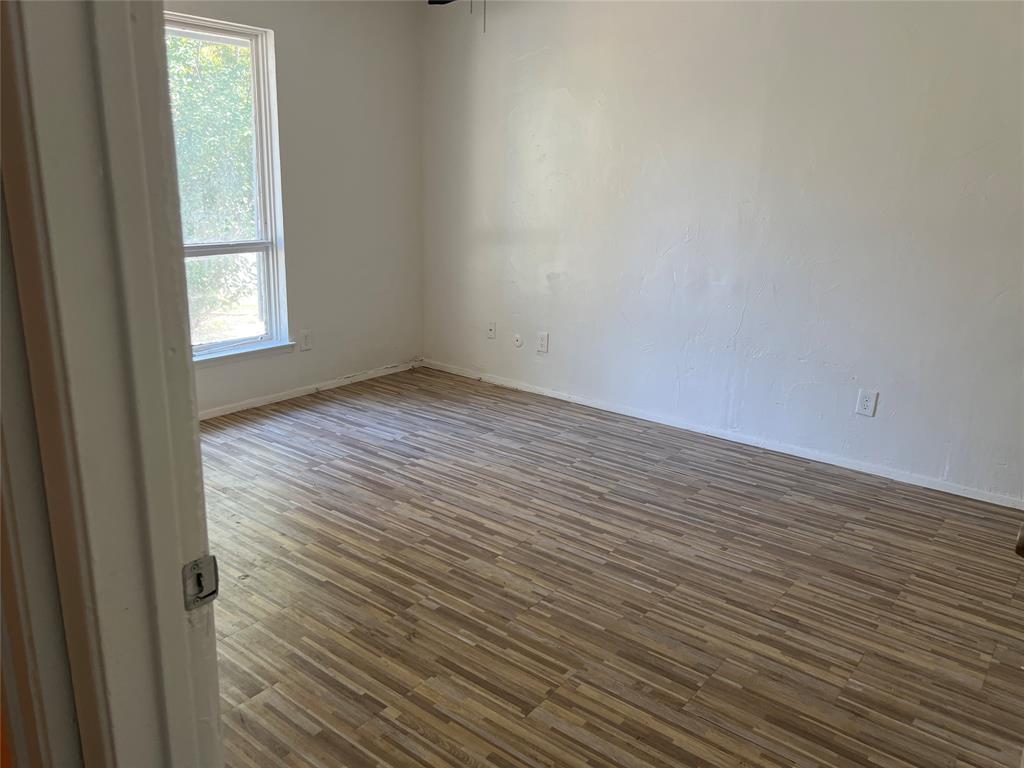 Room interior featuring wood-finish flooring, white walls, and a single-hung window