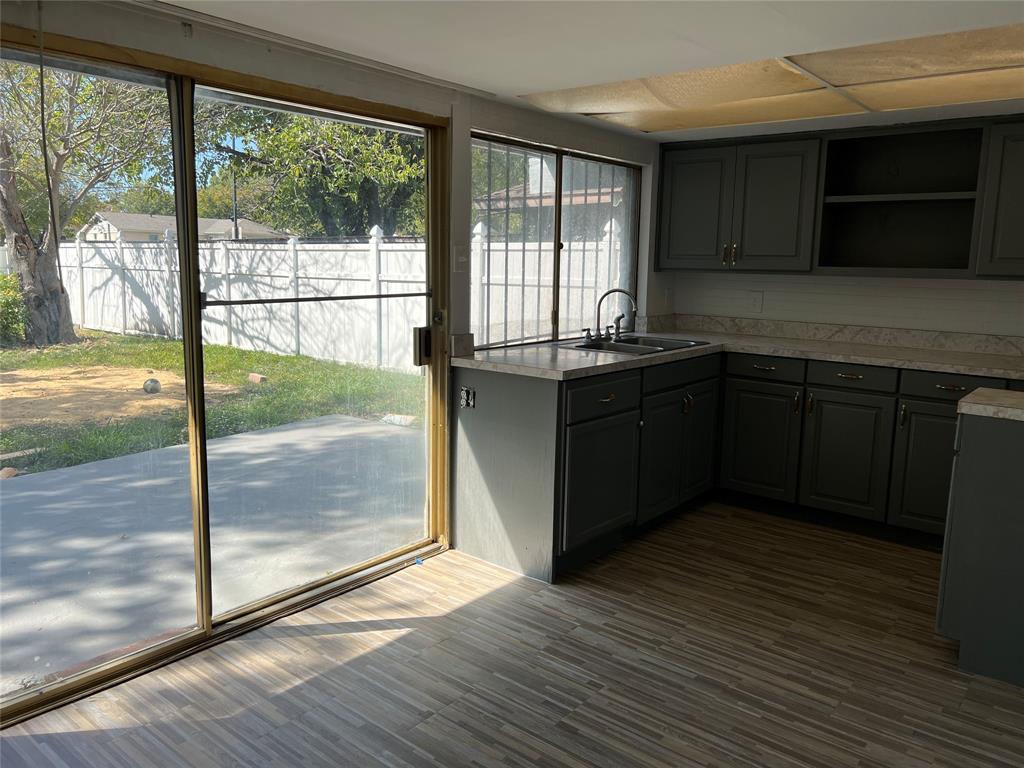 Kitchen featuring dark-toned cabinetry, light-colored countertops, wood-finish flooring, and large sliding glass doors opening to a concrete patio