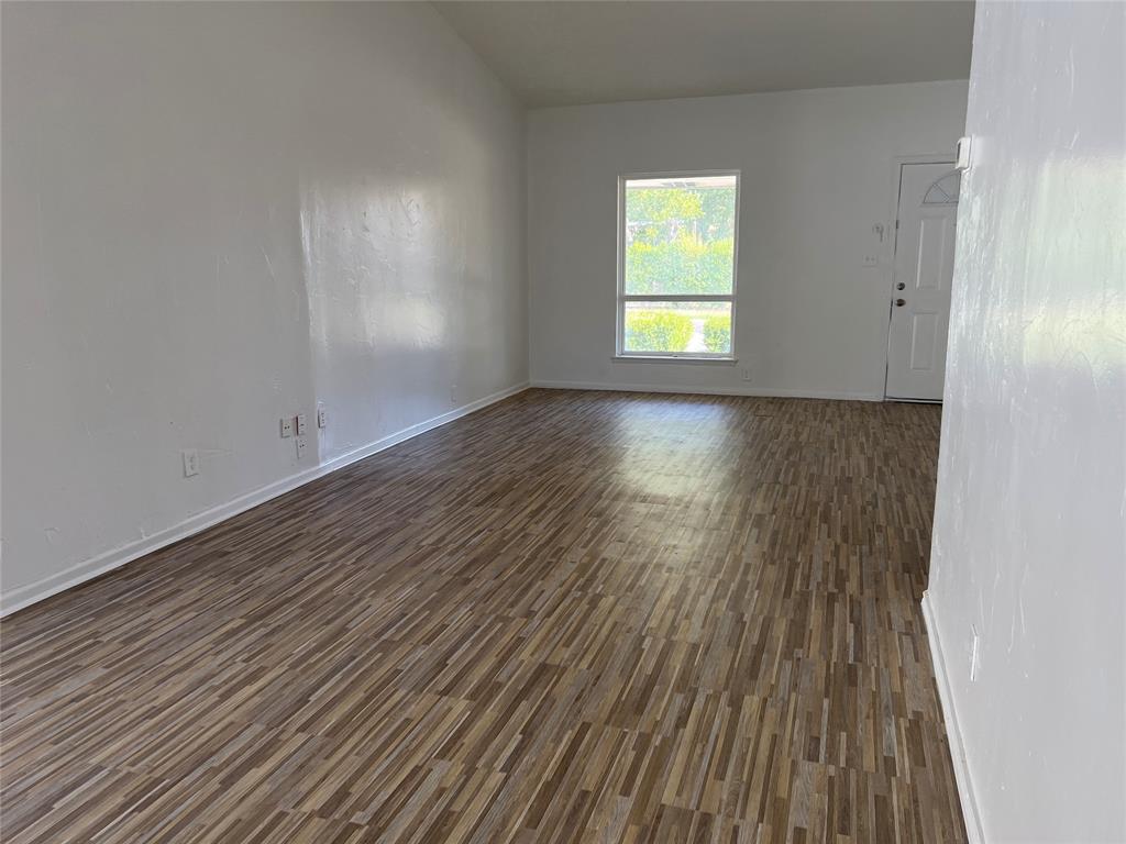 Interior space featuring wood-finish flooring, vaulted ceilings, neutral wall tones, and an exterior door with a window insert