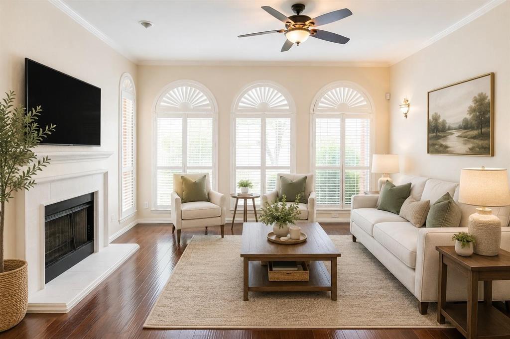 Bright, open living room with cozy fireplace, ceiling fan and soaring arched windows. Virtually staged.