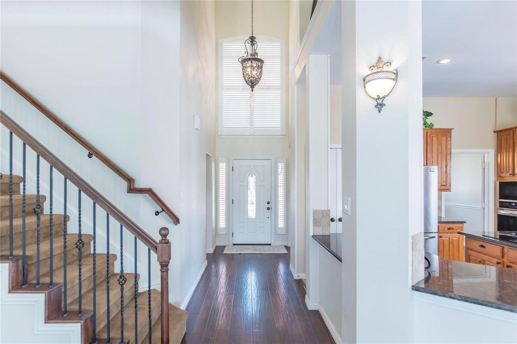 Dramatic entry with soaring ceilings, elegant staircase and wood floors.