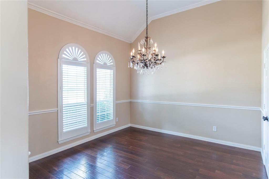 Formal dining or flex space with arched windows, chandelier and wood floors.
