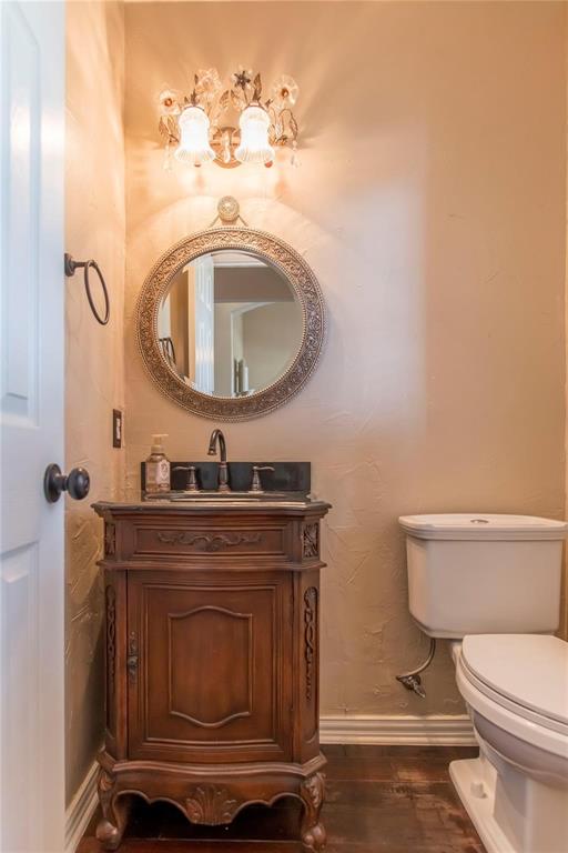 Chic half bath with wood vanity and decorative round mirror.