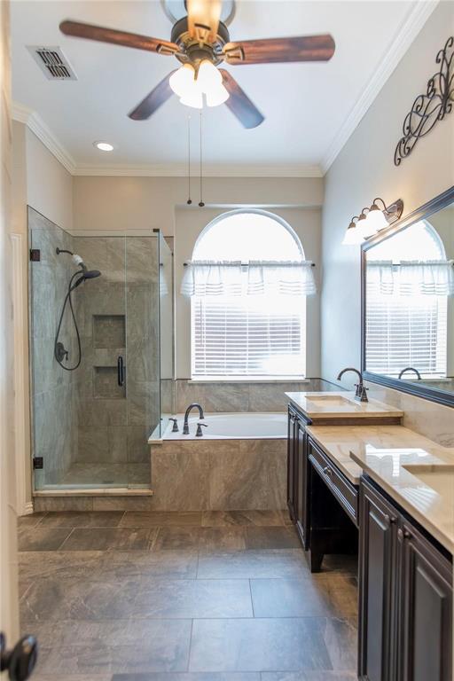 Bright bath with dual vanities, ceiling fan and natural window light.