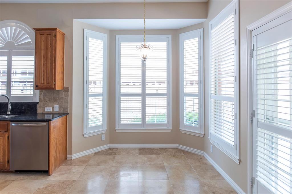 Light-filled dining area with a wall of windows and plantation shutters, open to the kitchen.