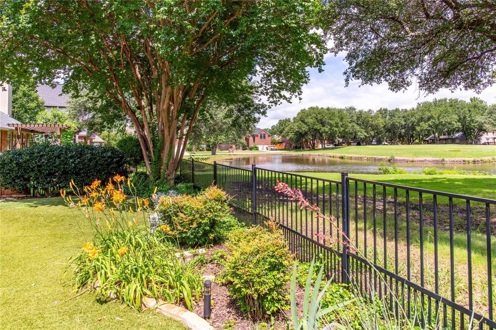 Beautifully landscaped yard with wrought-iron fencing and peaceful golf course and pond views beyond.