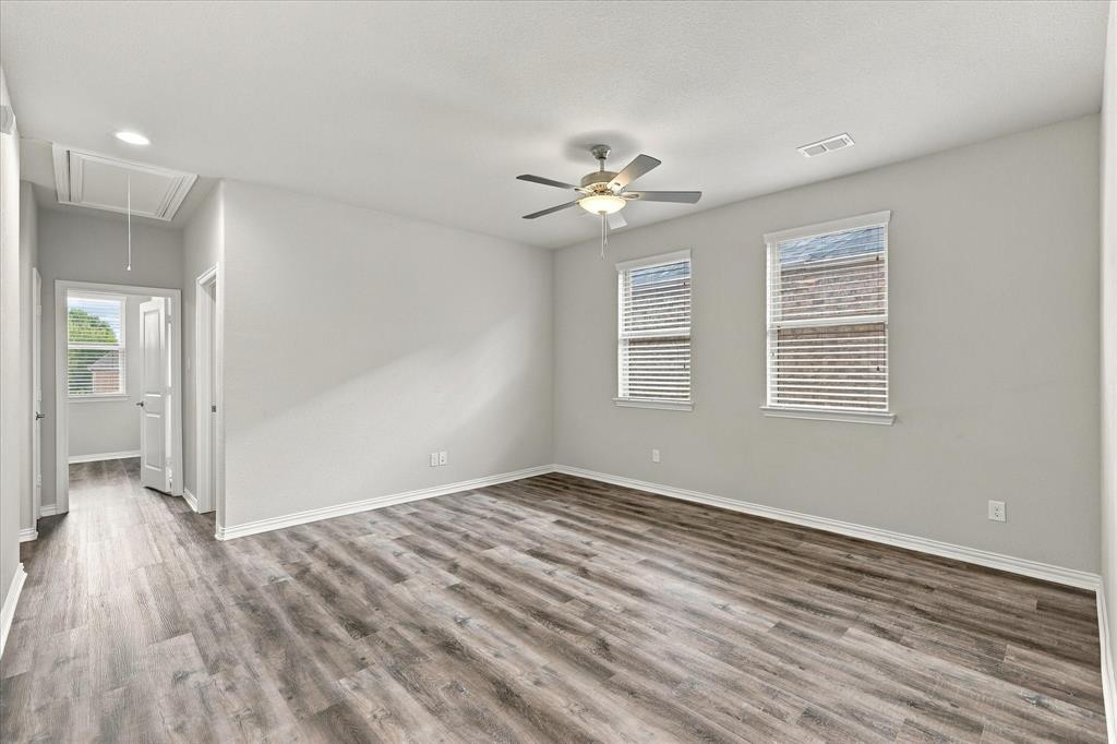 Wood-finish flooring, neutral wall tones, two dual-pane windows, and a central ceiling fan with integrated lighting