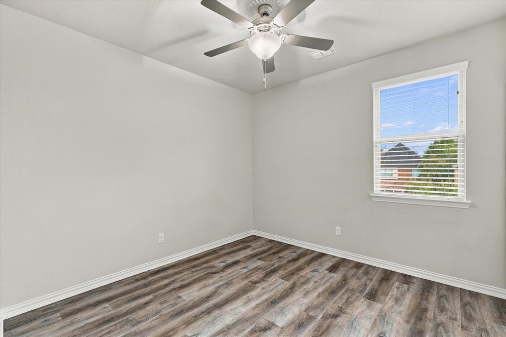 Neutral-toned interior featuring wood-finish flooring, a ceiling fan with integrated lighting, and a window with horizontal blinds
