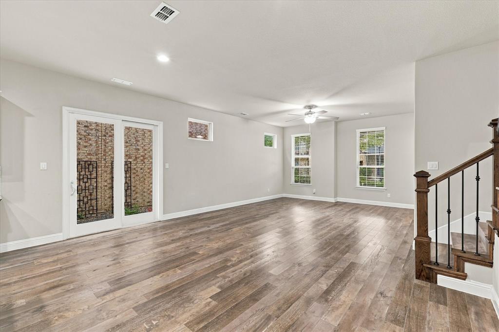 Open-concept interior featuring wood-finish flooring, sliding glass doors, recessed lighting, double-hung windows, and a staircase with iron balusters and a wood handrail