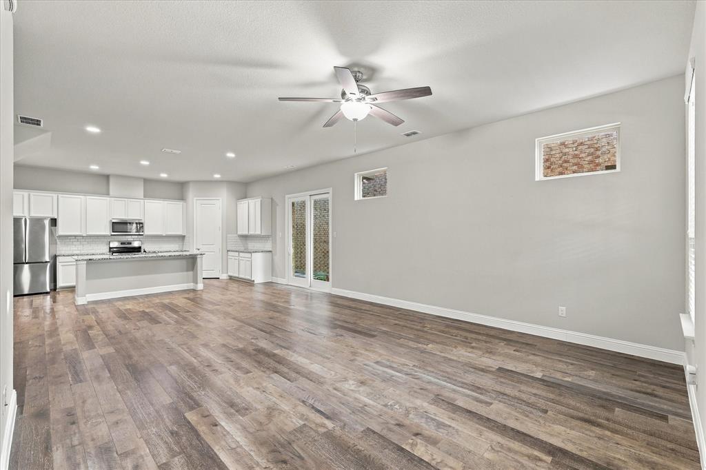 Open-concept room featuring wood-finish flooring, white cabinetry, recessed lighting, a ceiling fan with integrated light fixture, and glass-paneled exterior doors