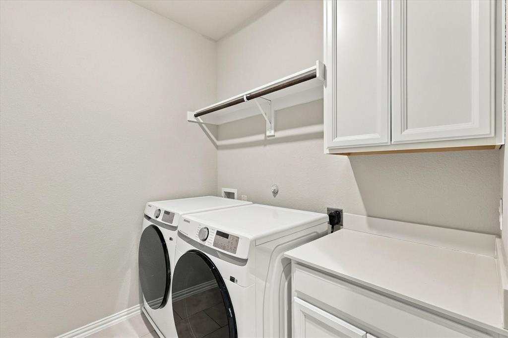 Laundry area featuring shaker-style white cabinetry, solid-surface countertop, and an integrated hanging rod with shelving