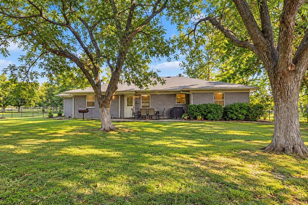 Rear exterior view of the home featuring the backyard and patio area.