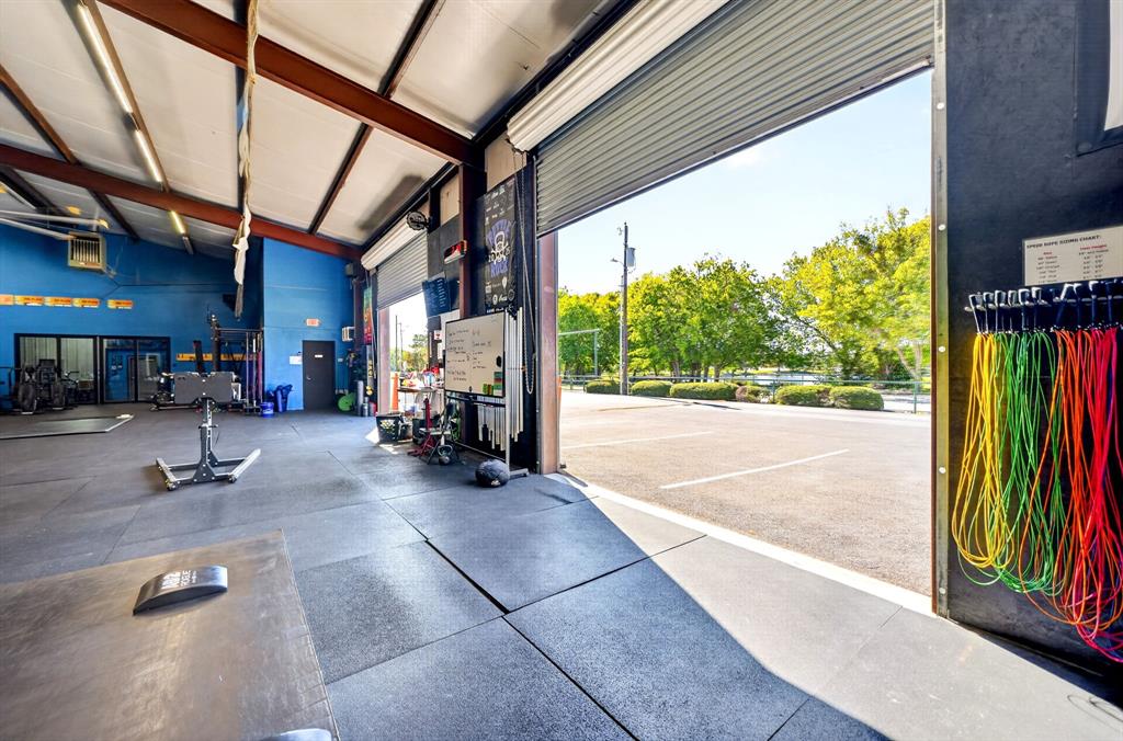 Expansive open-concept space featuring industrial metal structural beams, high-clearance ceilings, durable rubber flooring, and a large-format roll-up door opening to a paved parking area