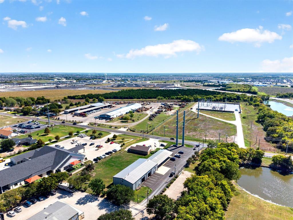 Aerial perspective of a multi-structure property featuring paved parking areas, covered storage bays, and open land space