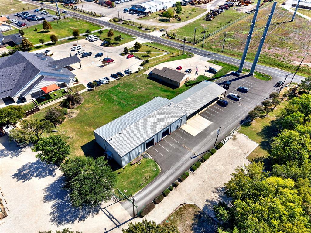 Industrial property featuring a metal building, dedicated covered parking, paved driveway, gated entry, and expansive grounds
