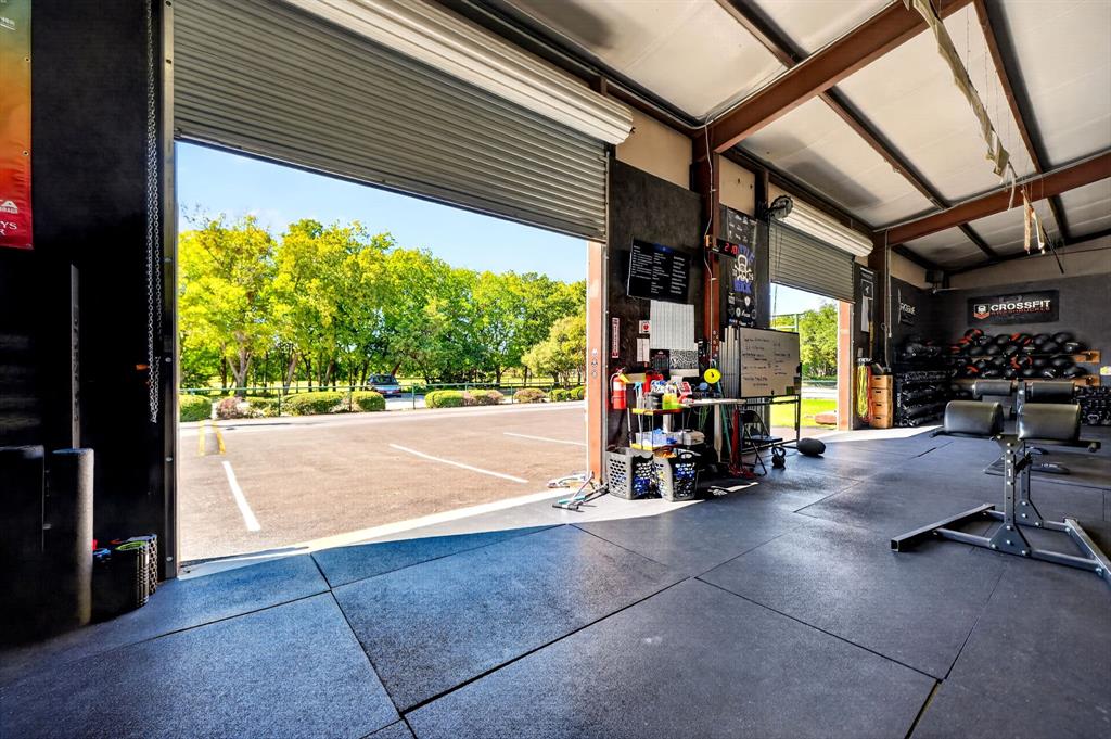 Industrial flex space featuring high ceilings with exposed steel beams, durable rubber flooring, and large roll-up bay doors