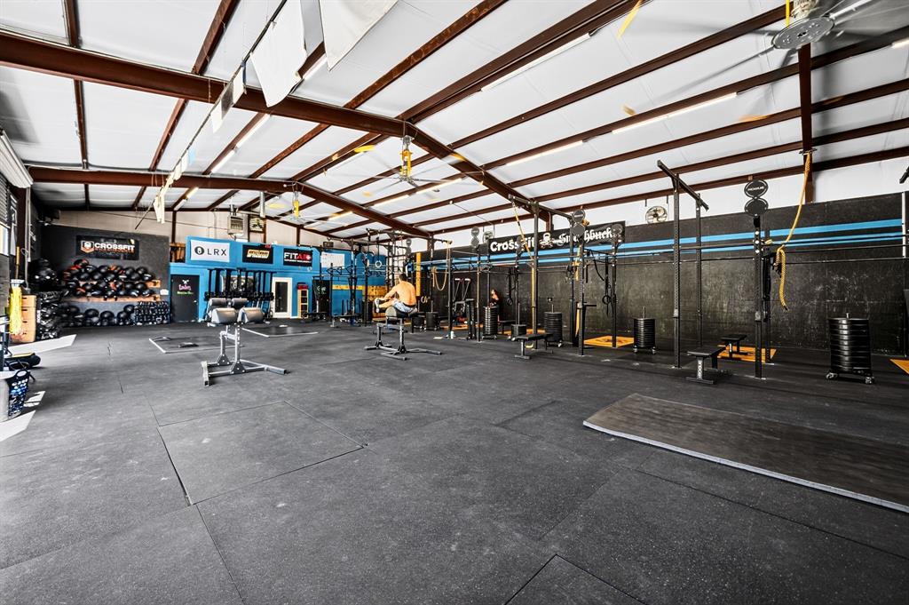 Expansive open-concept space featuring vaulted ceilings with exposed steel beams, industrial lighting fixtures, and high-durability rubber flooring