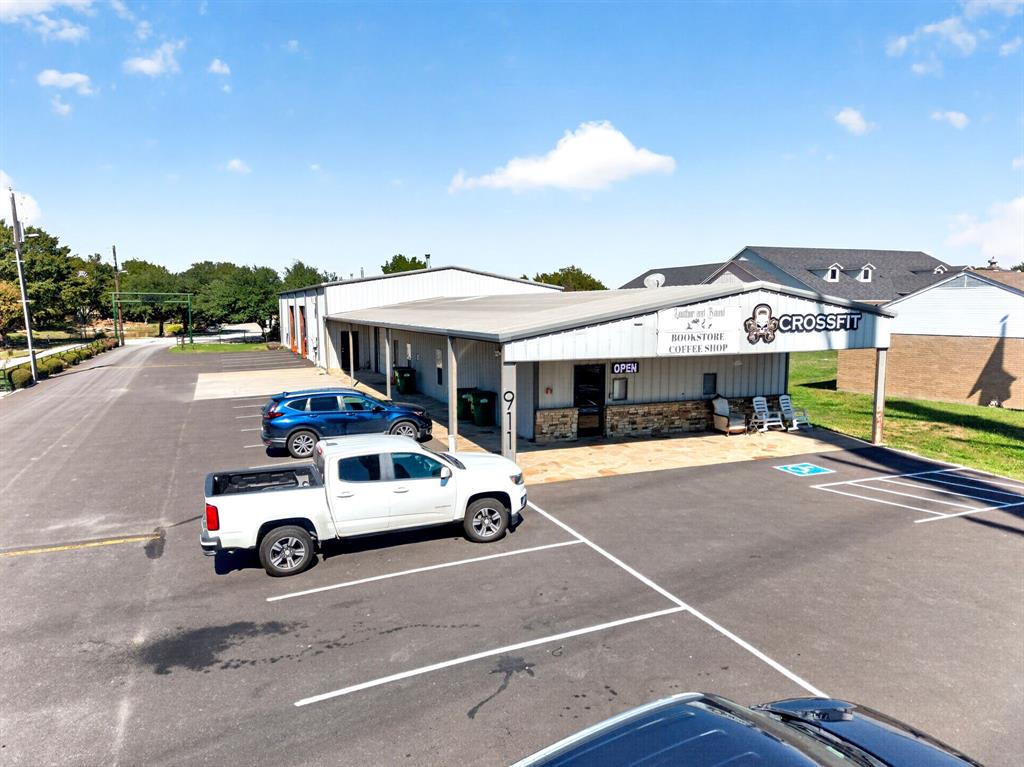 Commercial property exterior featuring metal siding, stone veneer accents, a covered entrance, and a dedicated asphalt parking area