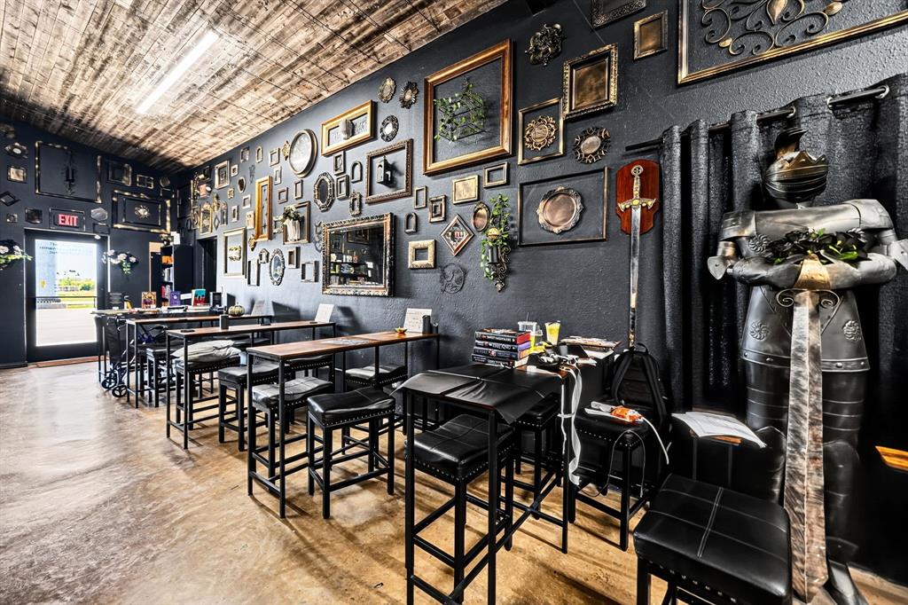 Textured dark-toned walls featuring decorative wall-mounted frames, wood-plank ceiling treatment, and concrete flooring