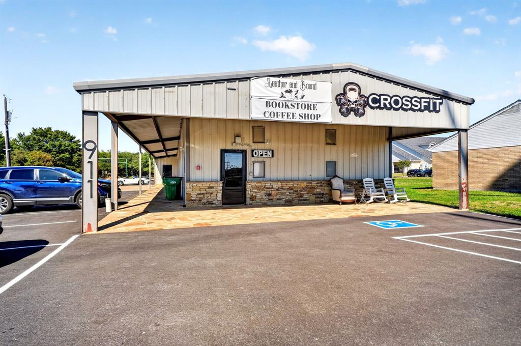 Commercial exterior featuring metal siding, stone veneer base, covered porch with stone paving, and asphalt-paved parking lot
