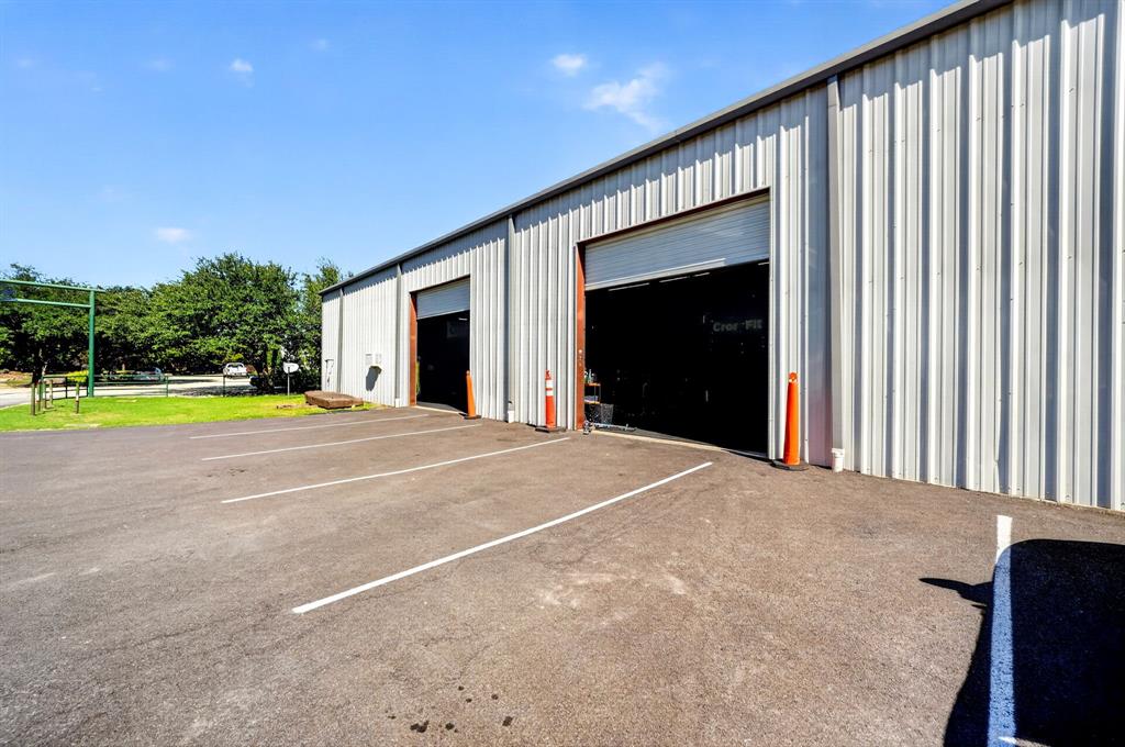Industrial exterior featuring metal siding, dual roll-up bay doors, and paved surface parking