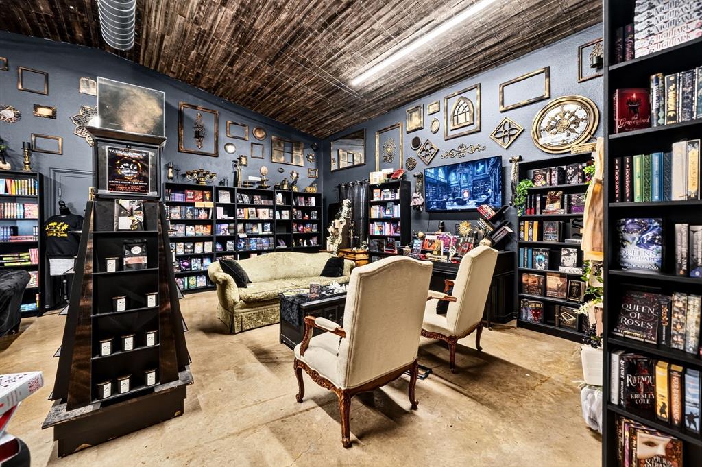 Interior space featuring wood-plank ceiling, wall-to-wall built-in shelving, and concrete flooring