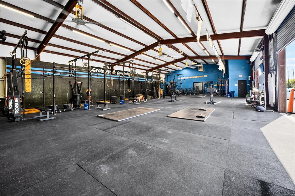 Expansive open-concept interior featuring exposed metal trusses, high-clearance ceilings, durable rubber flooring, and a large roll-up metal bay door