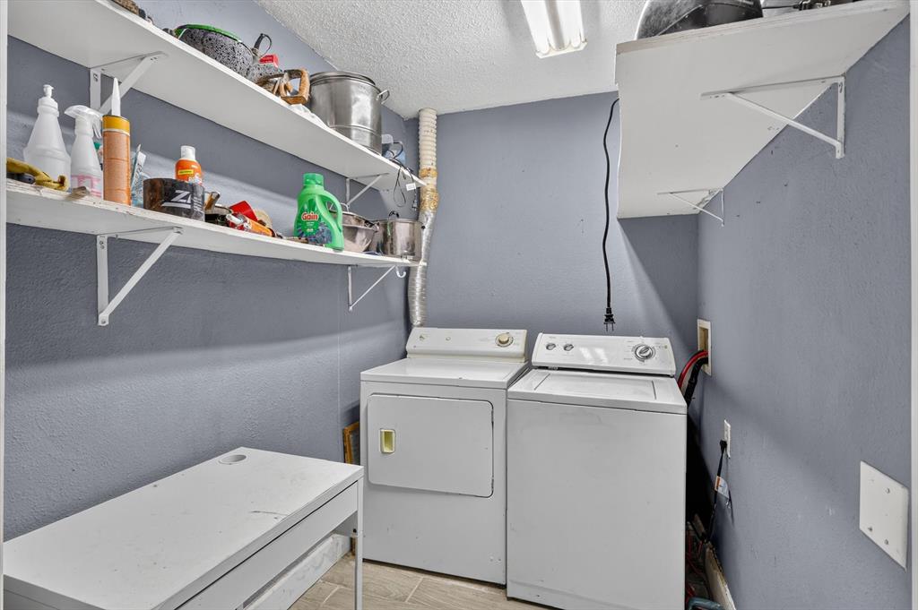 Laundry area featuring wall-mounted white shelving, tile flooring, and dedicated hookups for washer and dryer units