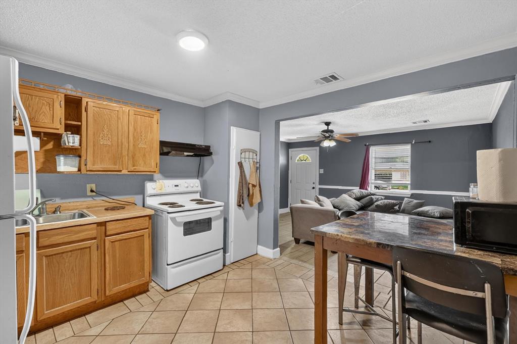 Kitchen featuring wood cabinetry, white range, tile flooring, and flush-mount ceiling lighting