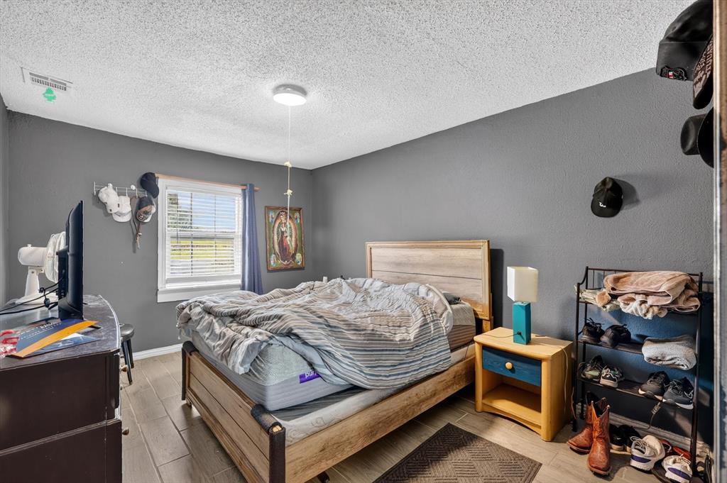 Bedroom interior featuring wood-finish tile flooring, textured walls, and a center-mounted flush mount light fixture