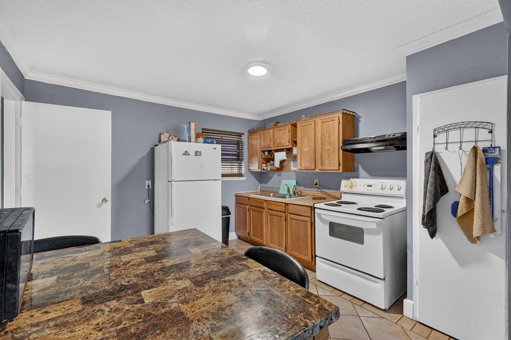 Kitchen featuring wood cabinetry, laminate countertops, a dual-basin sink, and tile flooring