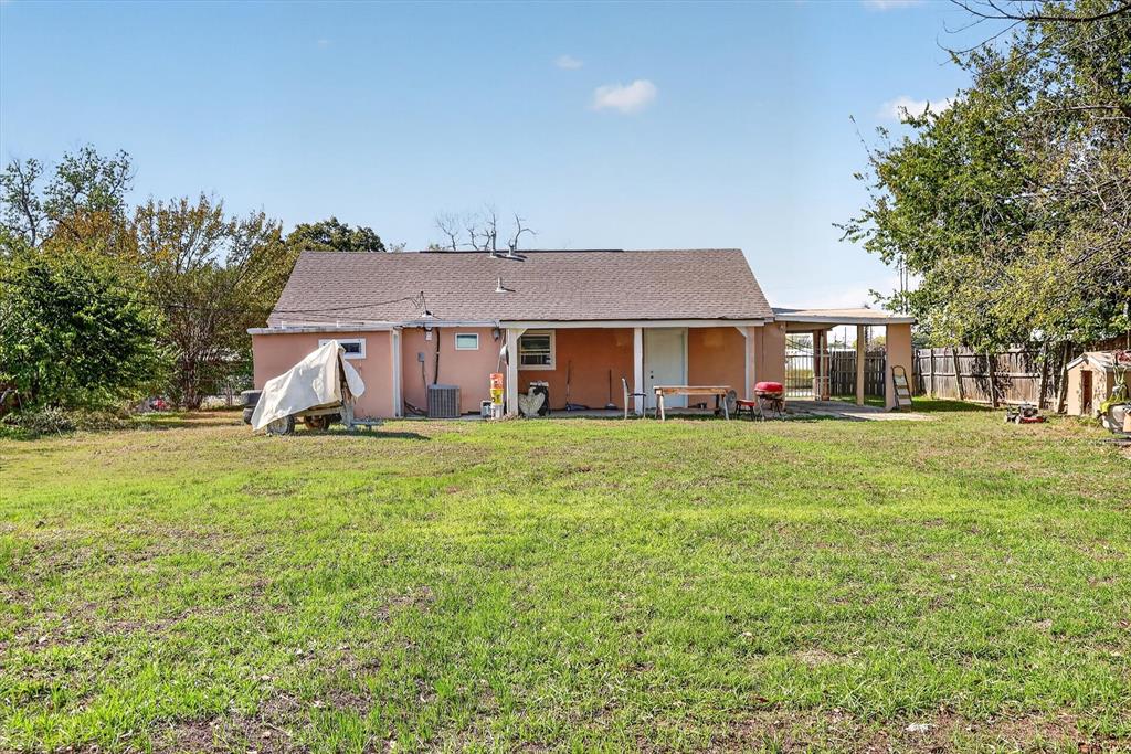 Rear exterior featuring a covered patio, attached carport, and an expansive grass lawn
