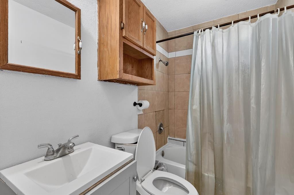 Bathroom featuring a vanity with an integrated basin, wood-finish wall-mounted cabinetry, a mirrored medicine cabinet, and a tiled shower surround with a built-in tub