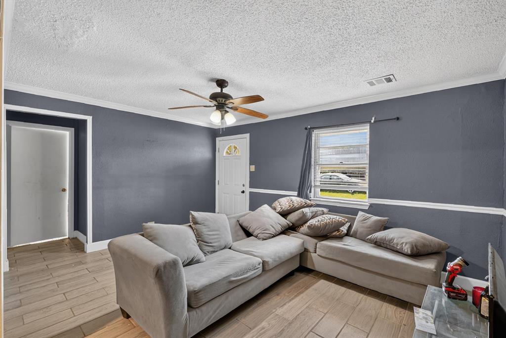 Interior space featuring wood-finish flooring, crown molding, chair rail trim, and a multi-blade ceiling fan with integrated lighting