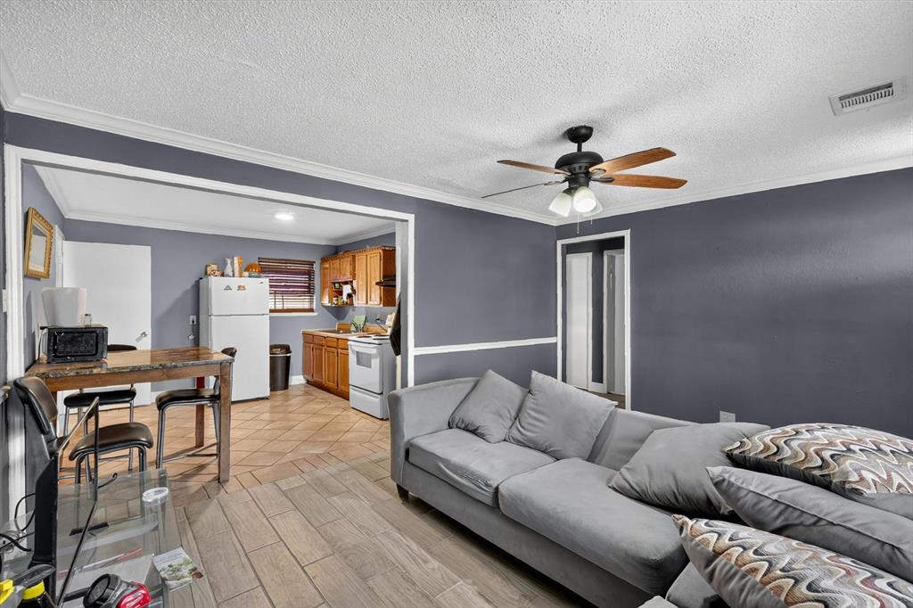 Interior space featuring wood-finish flooring, crown molding, chair rail trim, and a multi-light ceiling fan