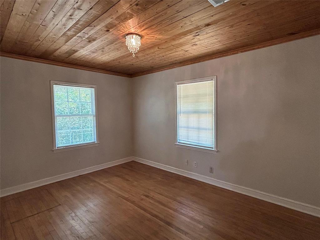Room featuring wood-plank ceiling, wood-finish flooring, and a crystal-style flush-mount light fixture