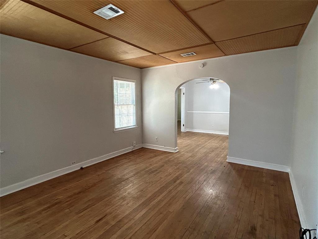 Interior space featuring wood-finish flooring, a paneled wood ceiling, and an arched entry