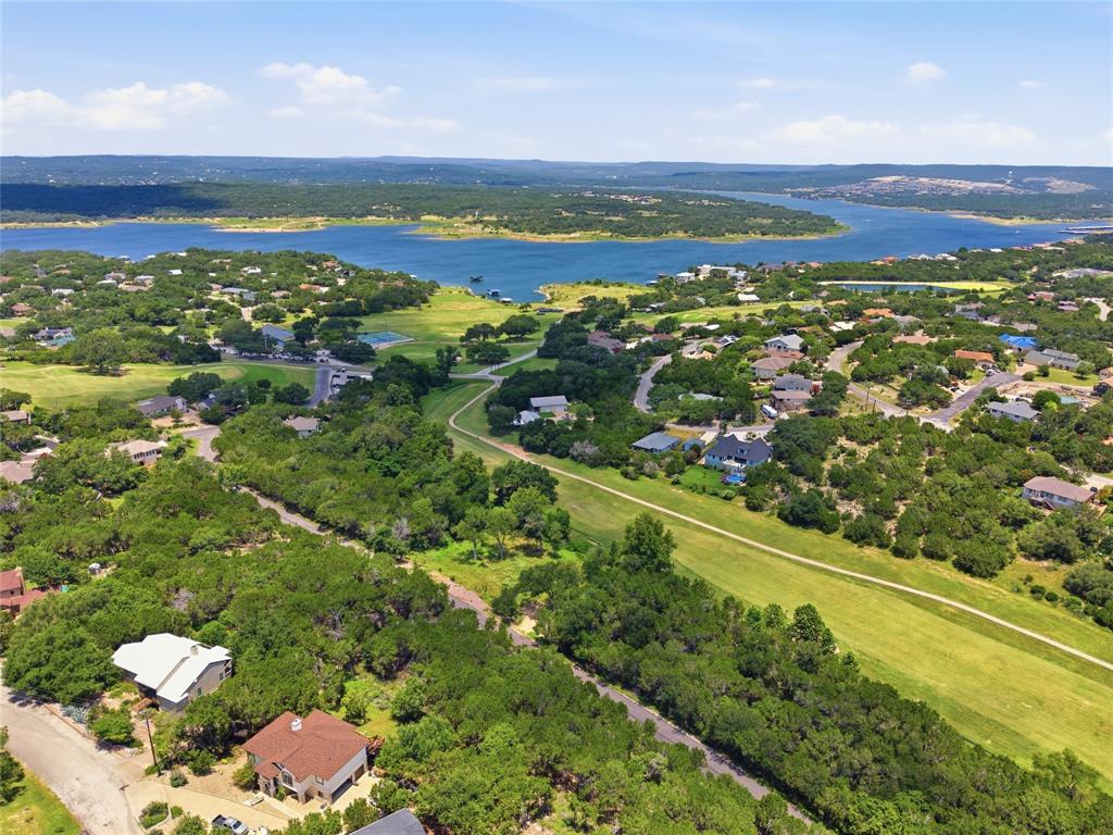 Aerial perspective featuring expansive lake frontage, mature tree canopy, and rolling topography