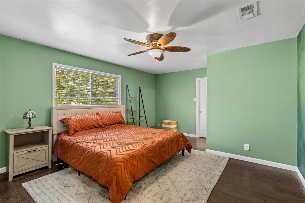 Room featuring wood-finish flooring, a ceiling fan with integrated lighting, and a large multi-pane window