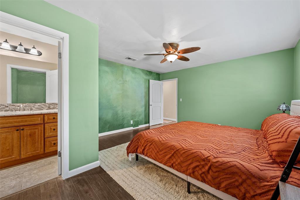 Bedroom featuring wood-finish flooring, a ceiling fan with integrated lighting, and a textured accent wall