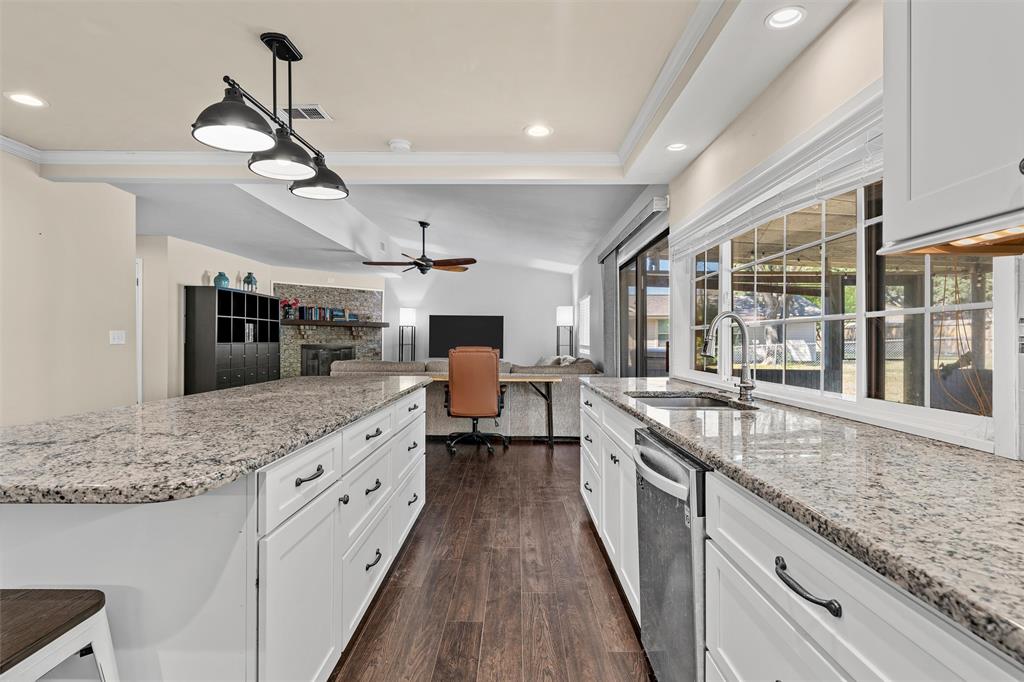 Kitchen featuring white cabinetry, stone-surface countertops, wood-finish flooring, a stainless steel faucet, and pendant lighting