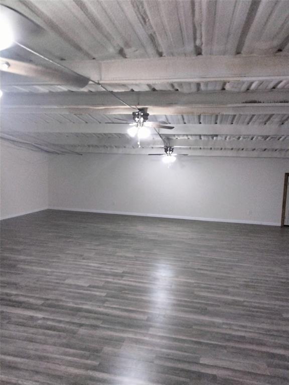 Open-concept space featuring wood-finish flooring, white-painted exposed beam ceiling, and dual ceiling fans with integrated lighting