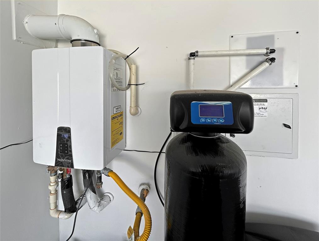 Wall-mounted tankless water heater paired with a whole-house water filtration system featuring a digital control interface