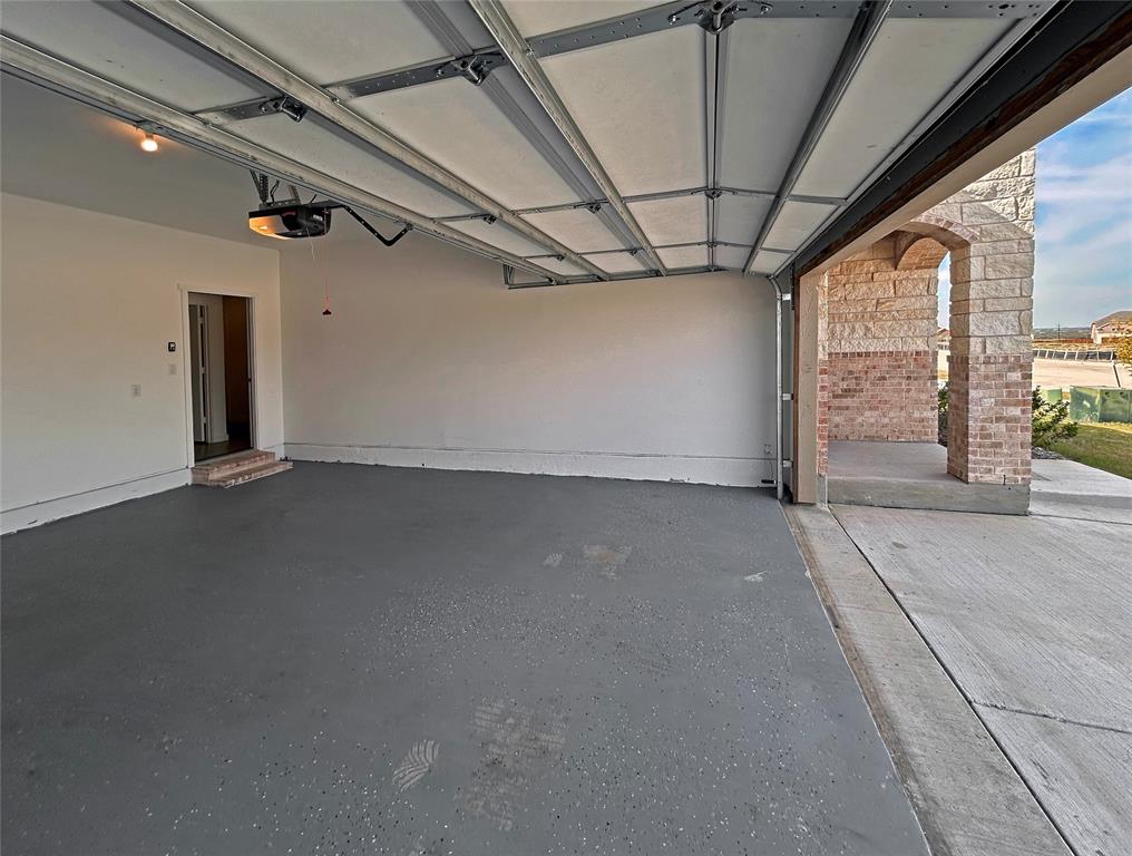 Garage featuring an epoxy-coated concrete floor, an overhead automatic door opener, and finished interior walls