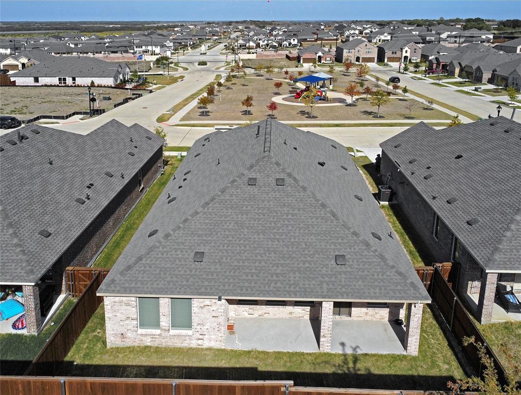 Aerial view featuring a brick exterior, covered rear patio, shingle roof, and a fenced backyard