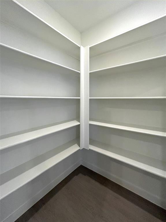 Storage space featuring white built-in wrap-around shelving and luxury vinyl plank flooring